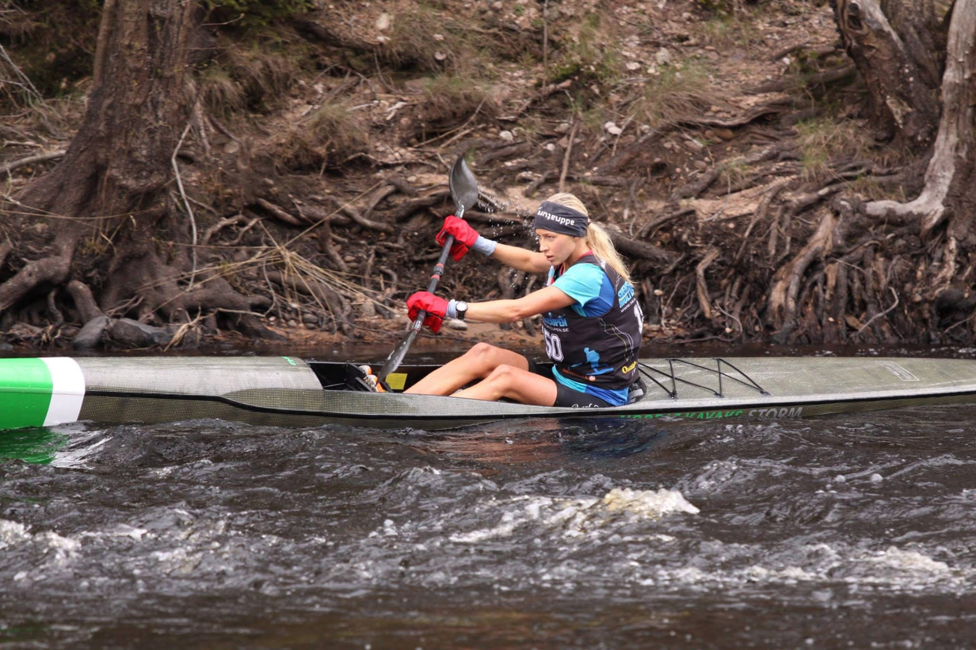 KRISTIN LARsson paddling a racing kayak down a river